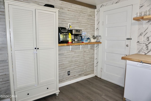 interior space with dark wood-type flooring, butcher block counters, and wood walls