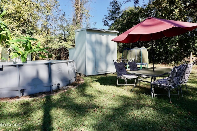 view of yard featuring a trampoline and a storage shed