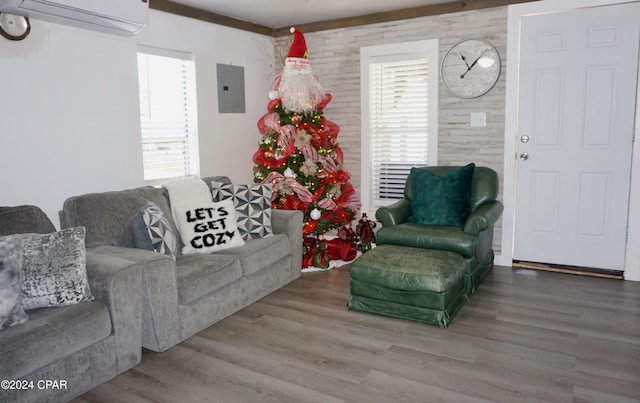 living room with electric panel, wooden walls, a wall mounted AC, and hardwood / wood-style flooring