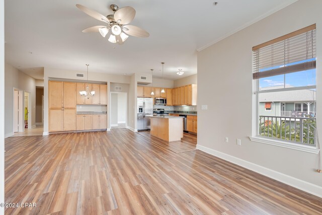 unfurnished living room featuring ceiling fan with notable chandelier, light hardwood / wood-style flooring, and ornamental molding