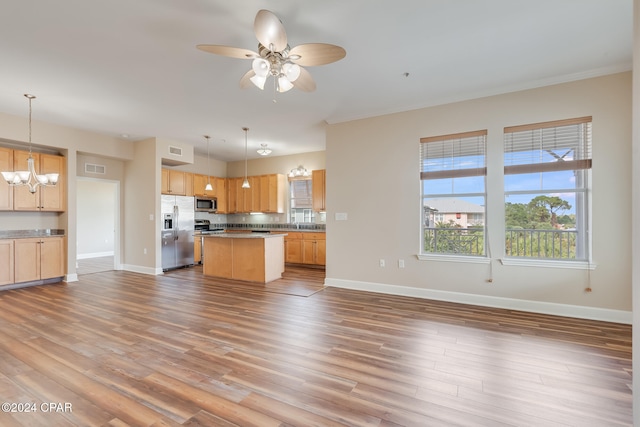 kitchen with pendant lighting, stainless steel appliances, a kitchen island, and wood-type flooring