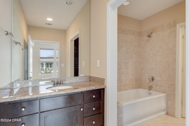 bathroom with tile patterned flooring, tiled shower / bath combo, and vanity