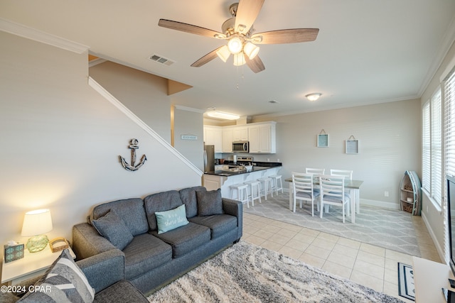 living room with crown molding, ceiling fan, and light tile patterned floors