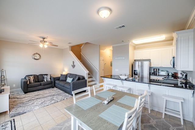 kitchen with kitchen peninsula, ornamental molding, stainless steel appliances, ceiling fan, and white cabinetry