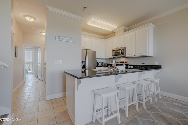 kitchen with kitchen peninsula, white cabinetry, stainless steel appliances, and ornamental molding