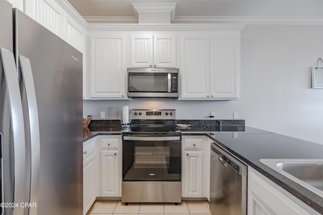 kitchen featuring light tile patterned flooring, dark stone countertops, appliances with stainless steel finishes, white cabinets, and ornamental molding