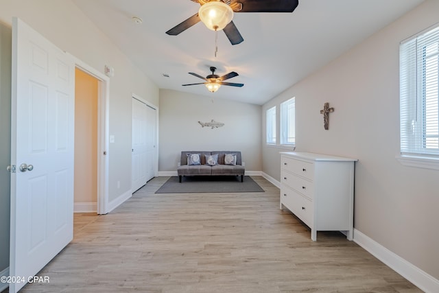 living area with light wood-type flooring, vaulted ceiling, plenty of natural light, and ceiling fan