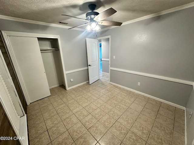 unfurnished bedroom with ceiling fan, ornamental molding, a textured ceiling, light tile patterned floors, and a closet