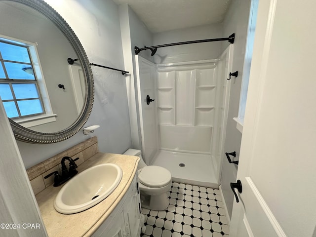 bathroom with toilet, a shower, and vanity