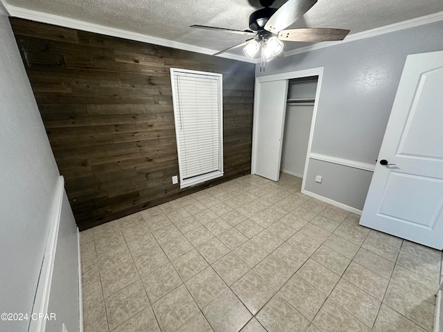 unfurnished bedroom featuring a textured ceiling, a closet, ceiling fan, and ornamental molding