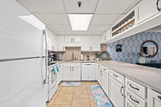 kitchen with white cabinets, a paneled ceiling, light tile patterned flooring, and white appliances