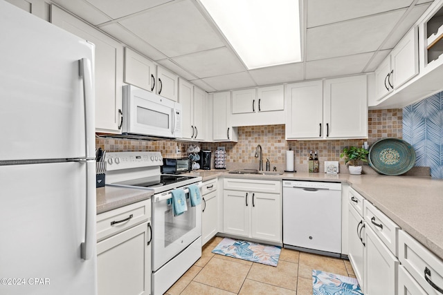 kitchen with a paneled ceiling, white cabinetry, light tile patterned floors, and white appliances