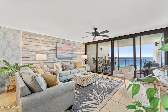 living room featuring light tile patterned floors, a water view, expansive windows, and ceiling fan