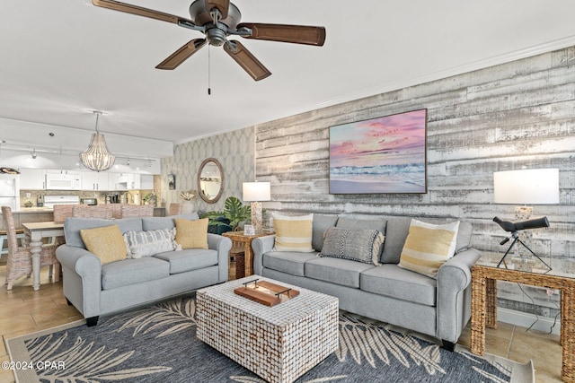 living room featuring tile patterned floors, crown molding, and ceiling fan with notable chandelier