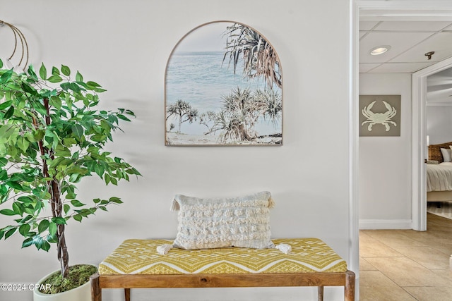 interior space with a water view, a drop ceiling, and light tile patterned flooring