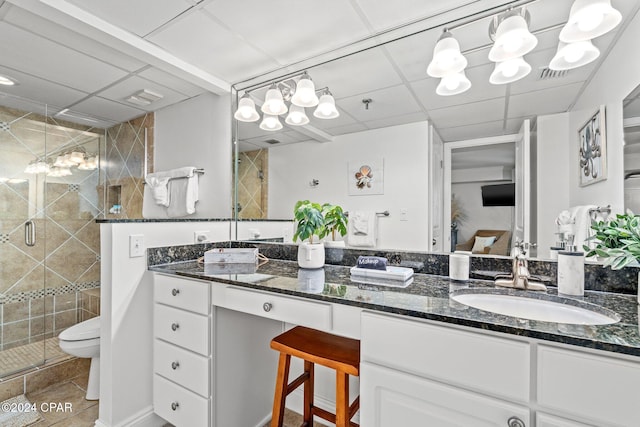 bathroom with a drop ceiling, vanity, a shower with door, tile patterned floors, and toilet