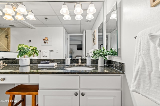 bathroom with a drop ceiling, walk in shower, and vanity