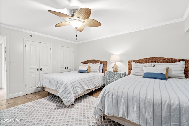 bedroom with ceiling fan, ornamental molding, light tile patterned floors, and multiple closets