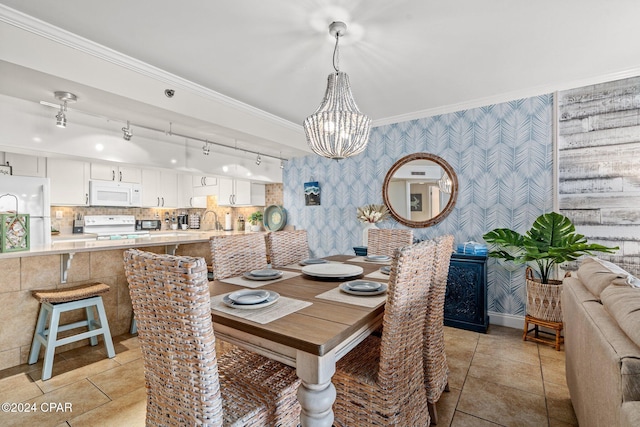 dining space with sink, an inviting chandelier, ornamental molding, and light tile patterned flooring