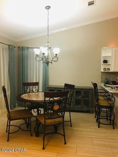 dining room featuring light hardwood / wood-style floors, crown molding, and an inviting chandelier