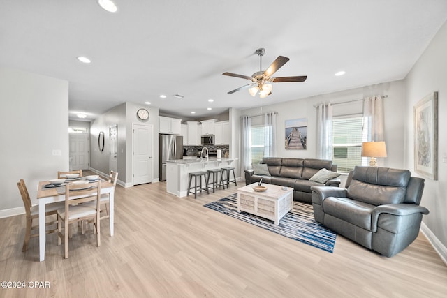 living room featuring ceiling fan, light hardwood / wood-style floors, and sink