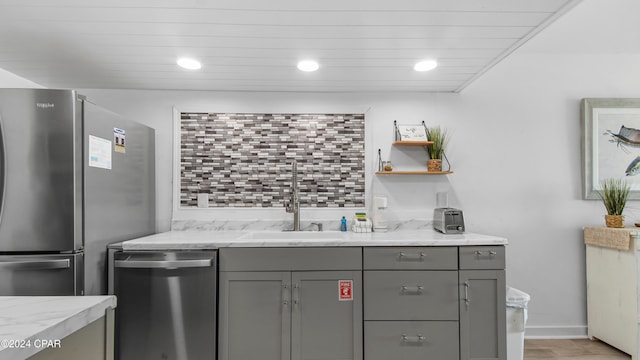 kitchen featuring gray cabinetry, light stone counters, sink, and stainless steel appliances