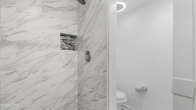 bathroom with tiled shower and toilet