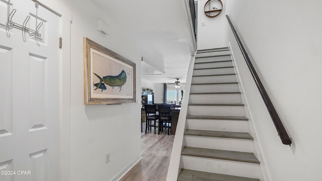 stairs with hardwood / wood-style flooring and ceiling fan