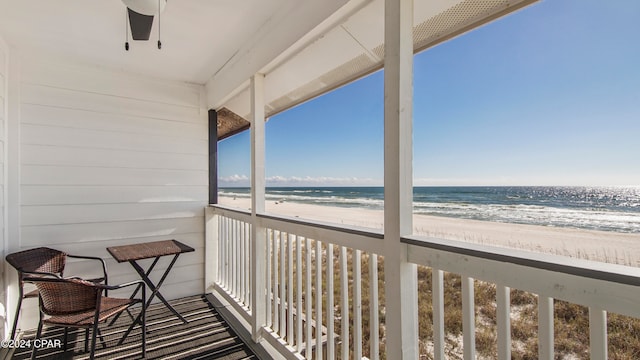 balcony featuring ceiling fan, a water view, and a beach view