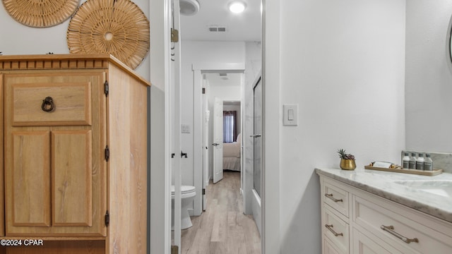 bathroom with walk in shower, toilet, vanity, and hardwood / wood-style flooring