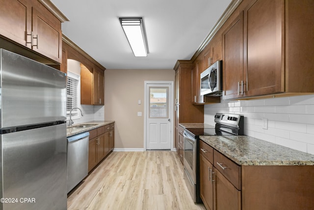 kitchen featuring sink, decorative backsplash, light wood-type flooring, stone countertops, and stainless steel appliances