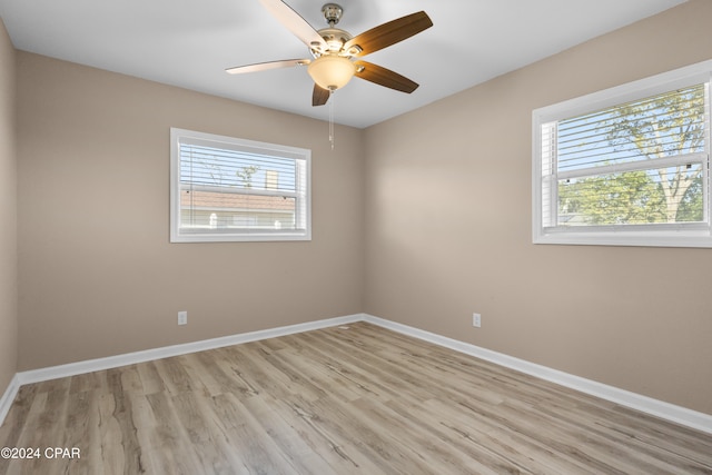 empty room with ceiling fan, a healthy amount of sunlight, and light wood-type flooring