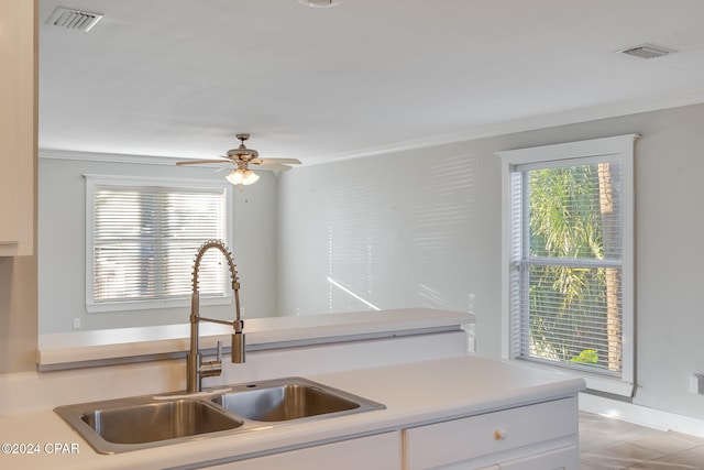 kitchen featuring ceiling fan, sink, light tile patterned flooring, crown molding, and white cabinets