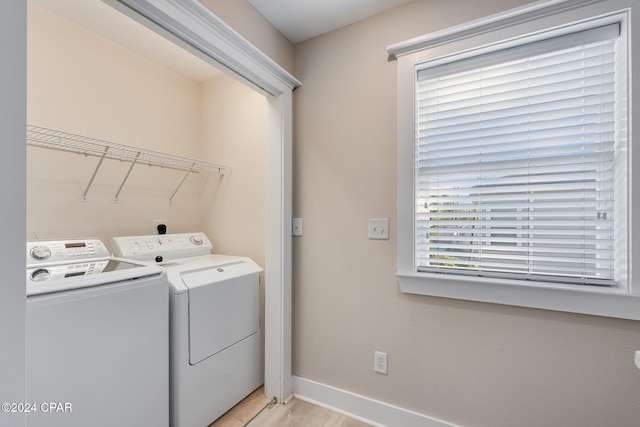 clothes washing area featuring washer and clothes dryer and light hardwood / wood-style floors