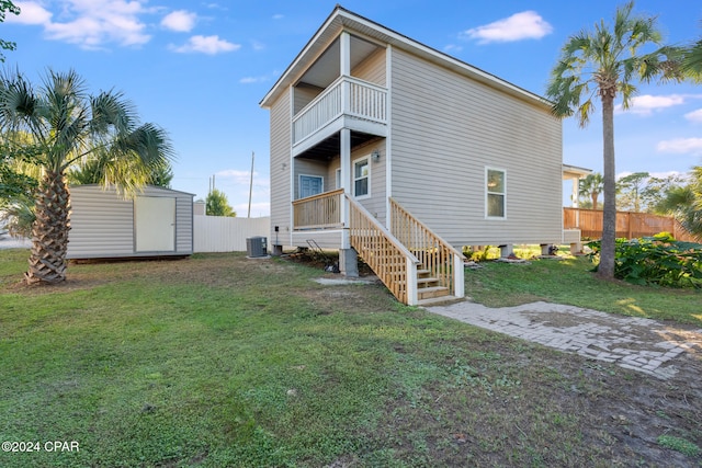 back of house with a lawn, a storage unit, a balcony, and central air condition unit