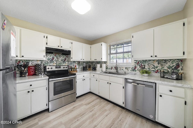 kitchen featuring sink, white cabinetry, backsplash, stainless steel appliances, and light hardwood / wood-style floors