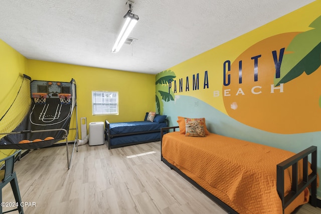 bedroom with a textured ceiling and light hardwood / wood-style floors