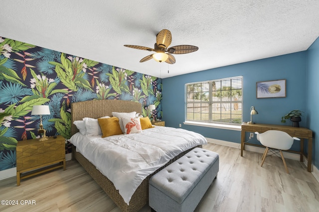 bedroom with ceiling fan, light hardwood / wood-style floors, and a textured ceiling