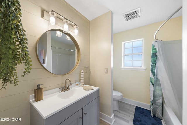 full bathroom featuring hardwood / wood-style flooring, shower / bathtub combination with curtain, vanity, and toilet