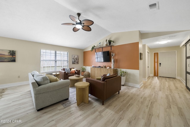 living room with ceiling fan, light hardwood / wood-style floors, vaulted ceiling, and a textured ceiling