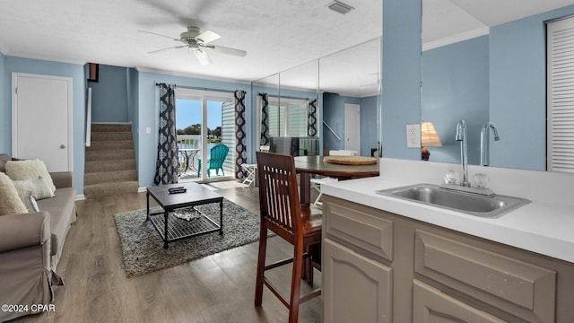 kitchen featuring ceiling fan, sink, ornamental molding, and light hardwood / wood-style flooring