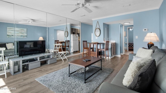 living room featuring ceiling fan, hardwood / wood-style floors, and crown molding