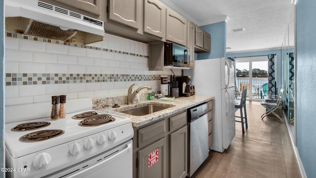 kitchen featuring decorative backsplash, stainless steel appliances, crown molding, sink, and light hardwood / wood-style floors