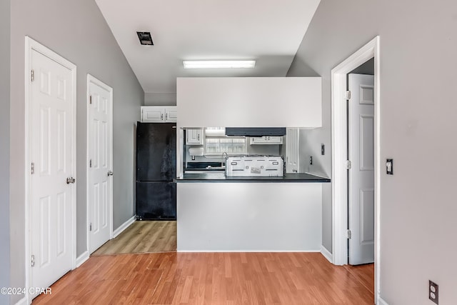 kitchen featuring lofted ceiling, white stove, white cabinets, black refrigerator, and light hardwood / wood-style floors