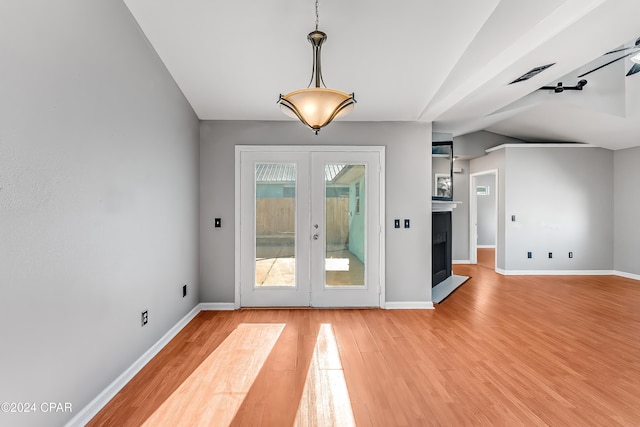 doorway with hardwood / wood-style floors, lofted ceiling, and french doors