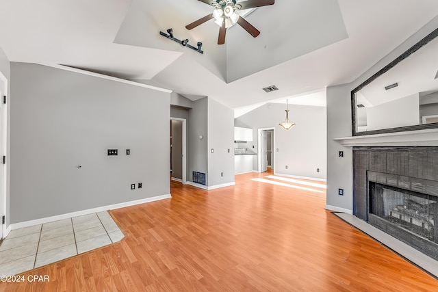 unfurnished living room with lofted ceiling, ceiling fan, light wood-type flooring, and a fireplace