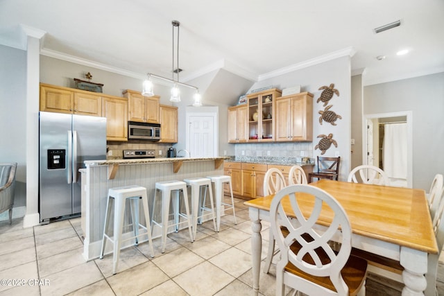 kitchen featuring hanging light fixtures, light tile patterned floors, decorative backsplash, a kitchen island, and appliances with stainless steel finishes