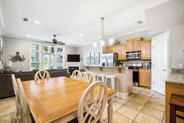 tiled dining area featuring ceiling fan and crown molding