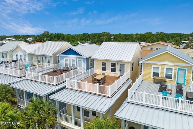 back of house featuring metal roof, a standing seam roof, and a residential view