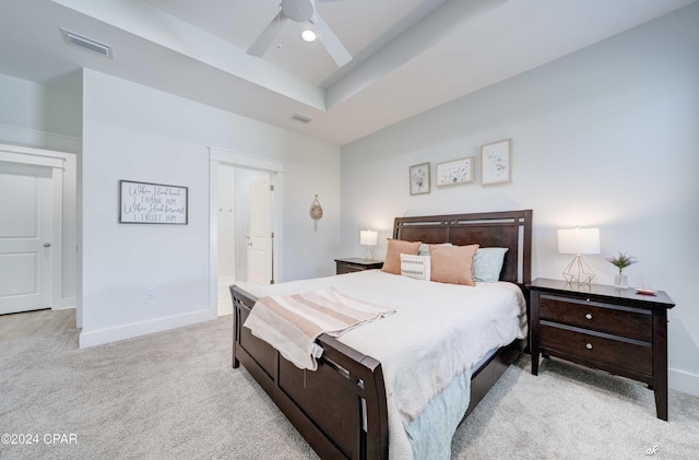 carpeted bedroom featuring a tray ceiling, ensuite bath, and ceiling fan